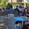 students on campus sitting and talking in a courtyard area with tables