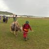 Dan Knight waves as he takes a ride on a yak in Harhorin, Mongolia