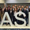 The student chapter poses for a group photo behind a SASE sign in a hotel lobby
