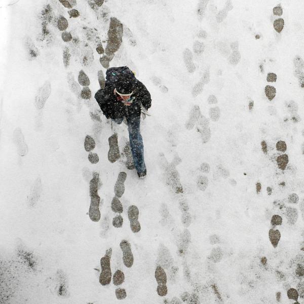 Aerial view of student walking on snowy path.