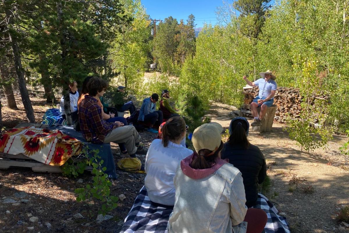 ENRP Specialization Lead Gregor Macgregor speaks to a group of students in the woods.