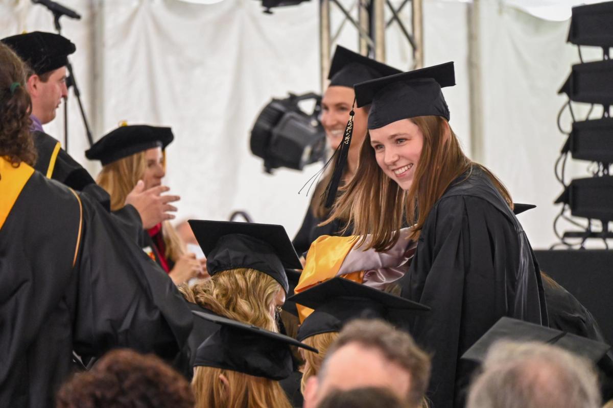 Student in graduation cap smiling in crowd of students.