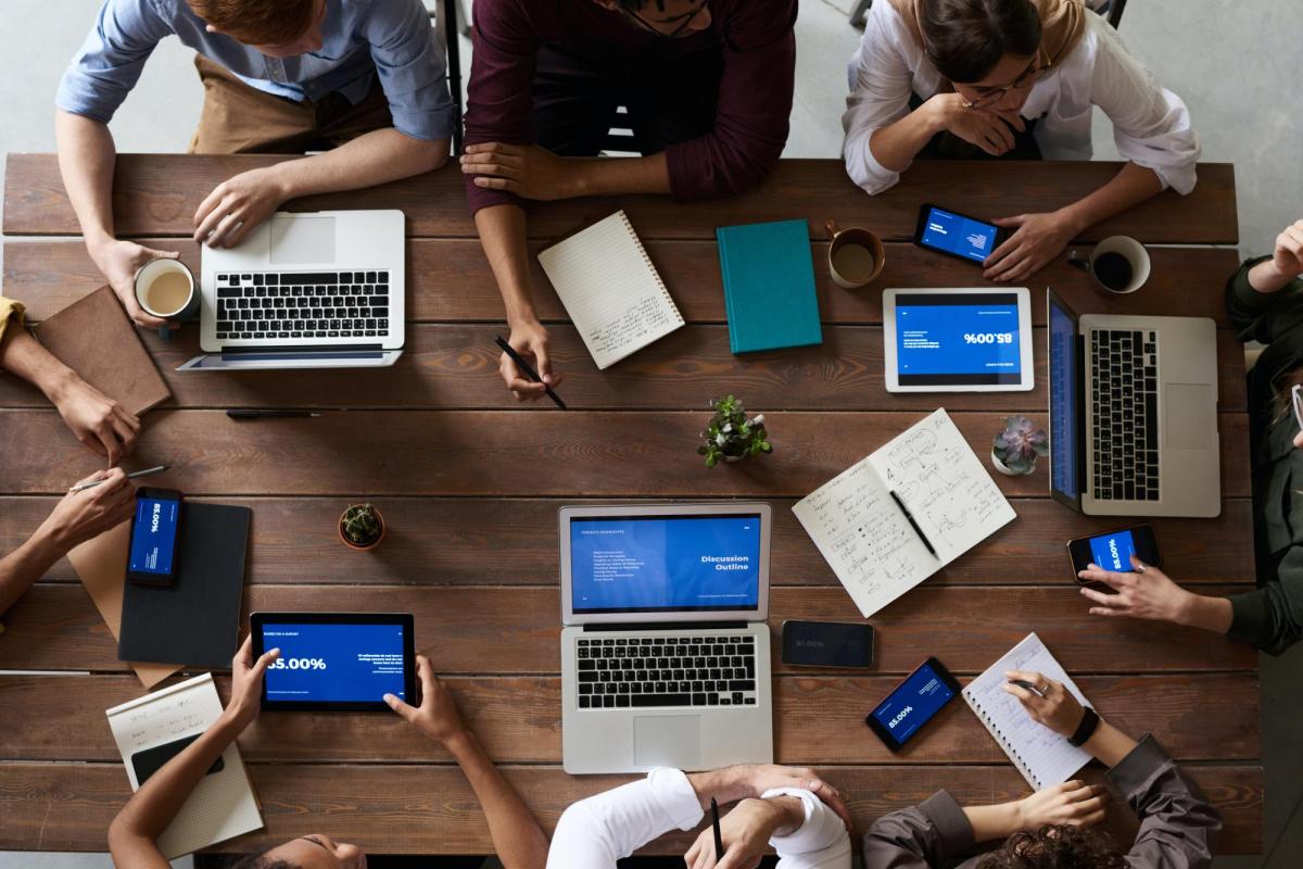 Overhead view of a table with laptops and tablets on it.