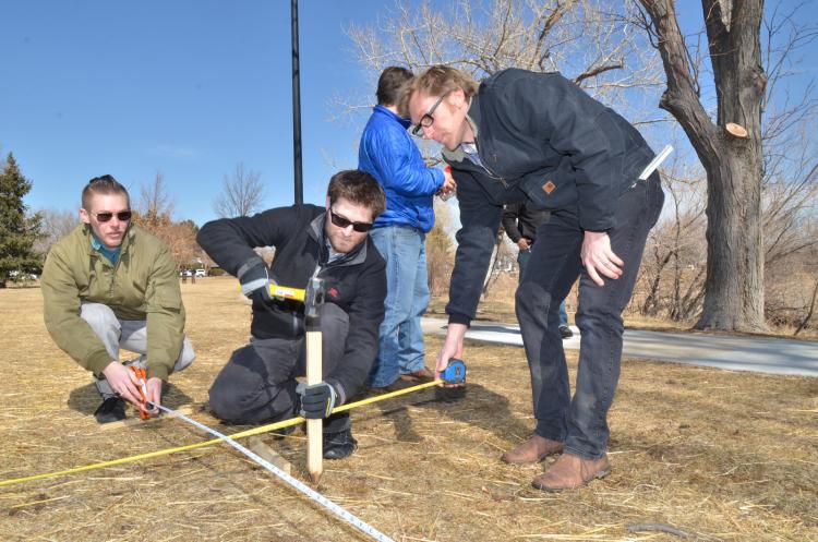 Engineers measuring and installing a stake in the ground.