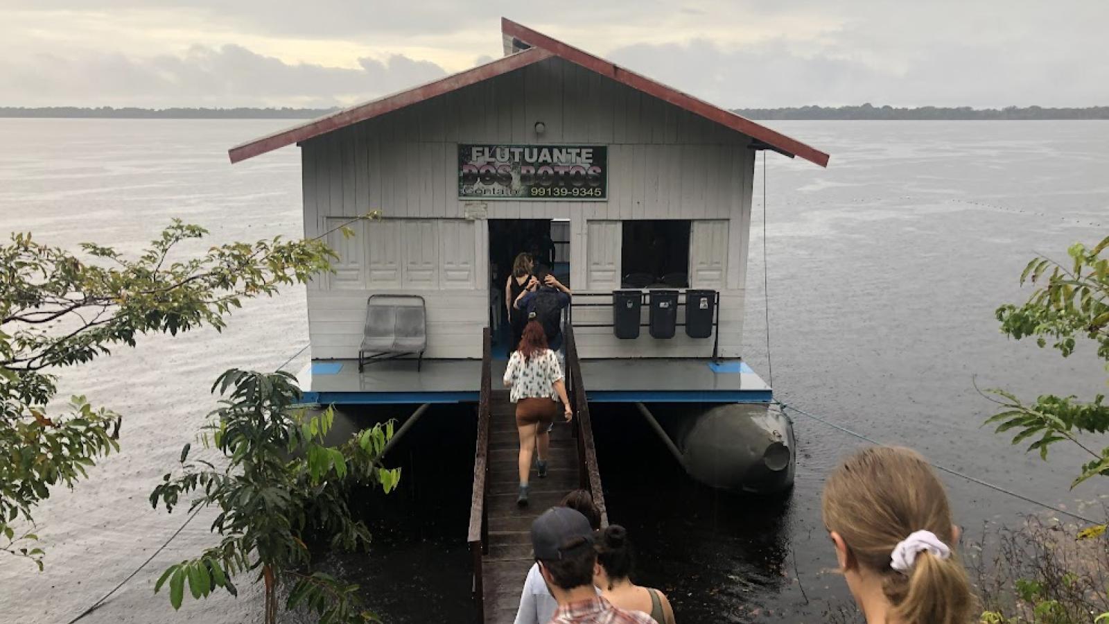 students walking into small hut over water. 
