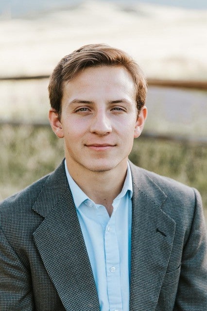 Dylan McNally in suit with mountain in background