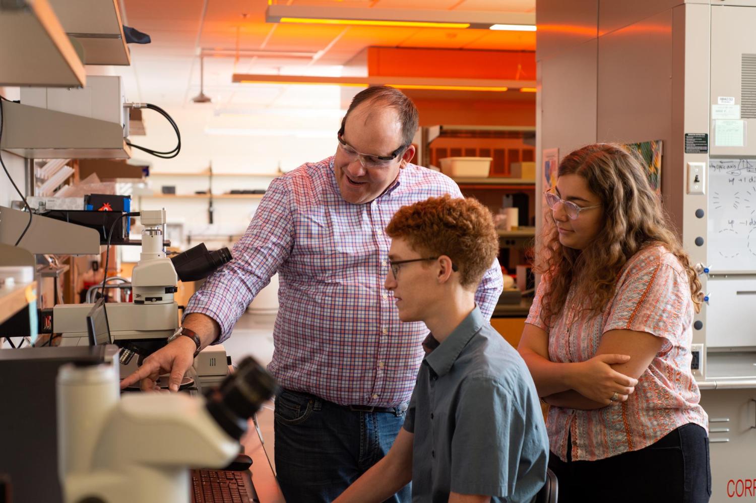 A faculty member working with two students in a lab.