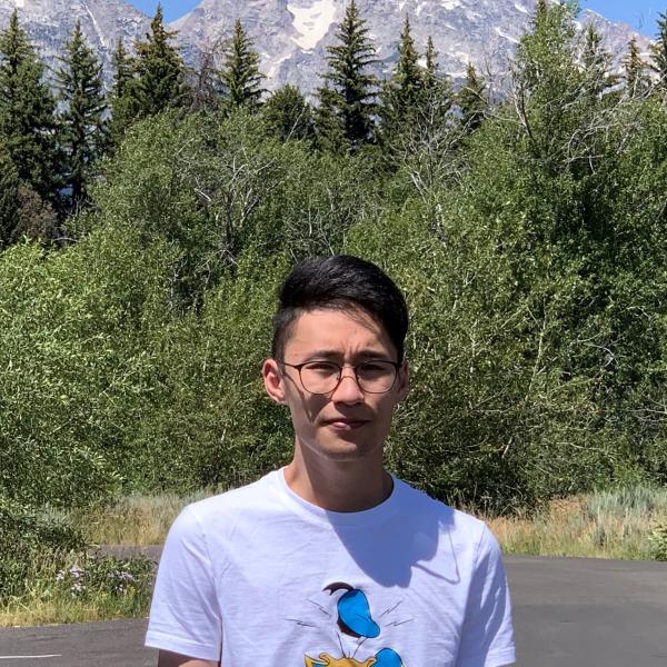 Wenhan Ou posing for photo outdoors with mountain in background