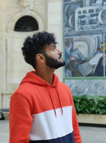 Rishabh Tennankore in front of a painting and archiectural feature