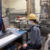 Student in hardhat in lab working at computer station