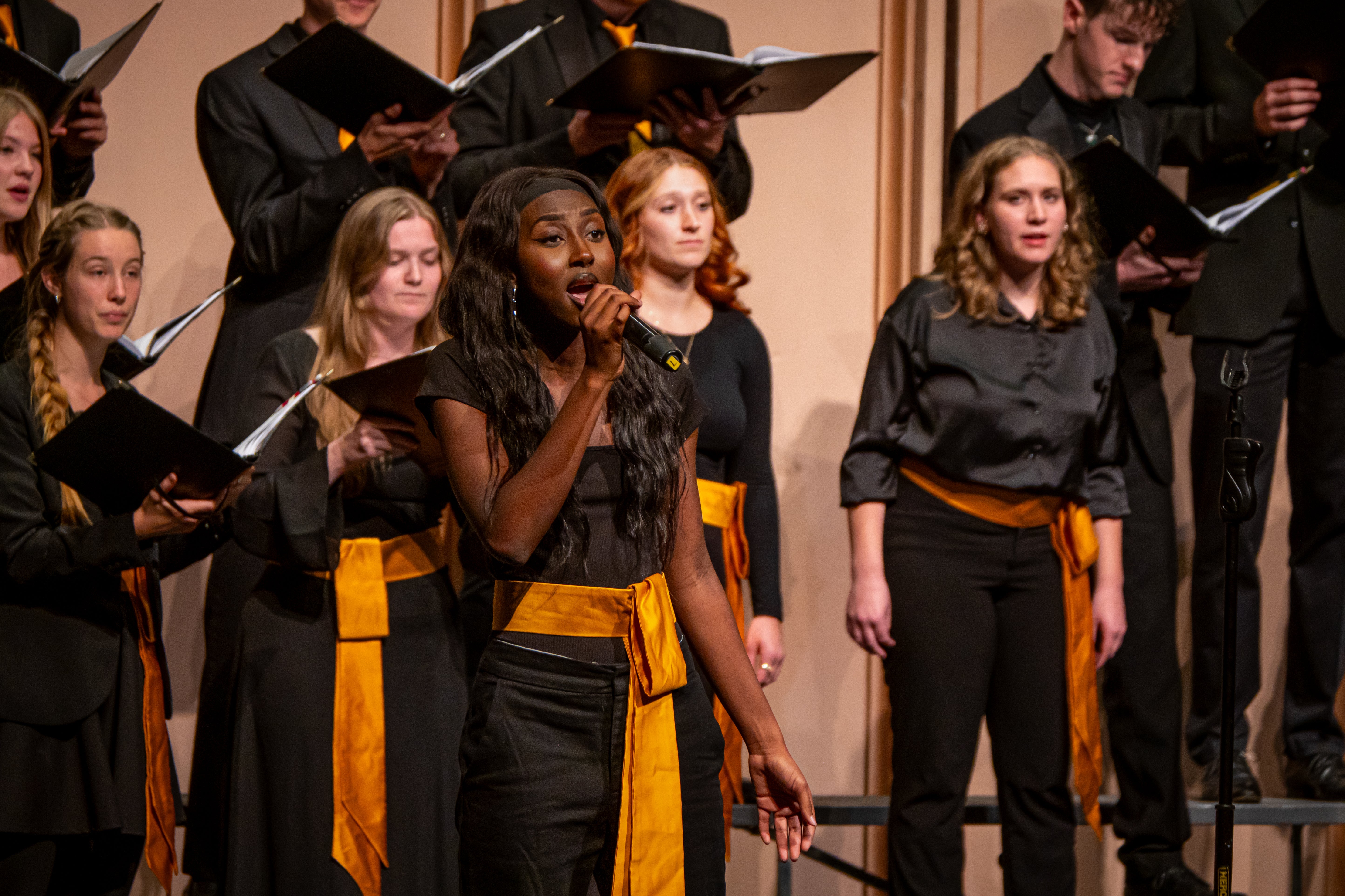 Vocal soloist on stage with choir at Macky Auditorium