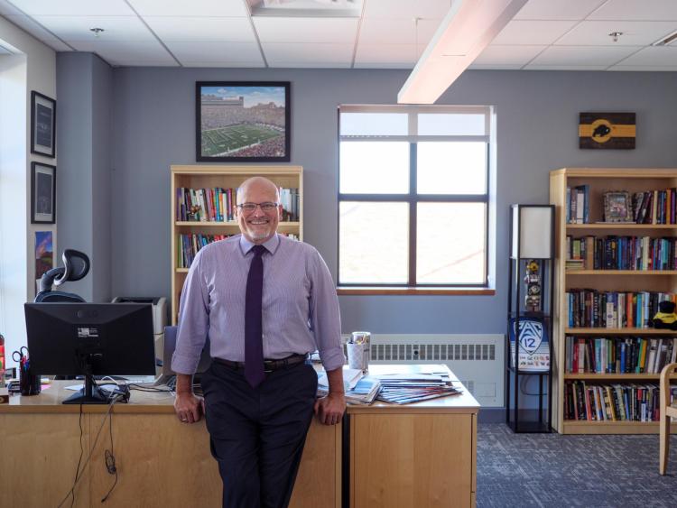 John Davis leaning on desk in his office