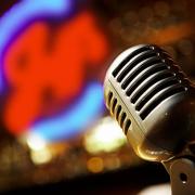 Vintage microphone with blurred neon jazz sign in the background