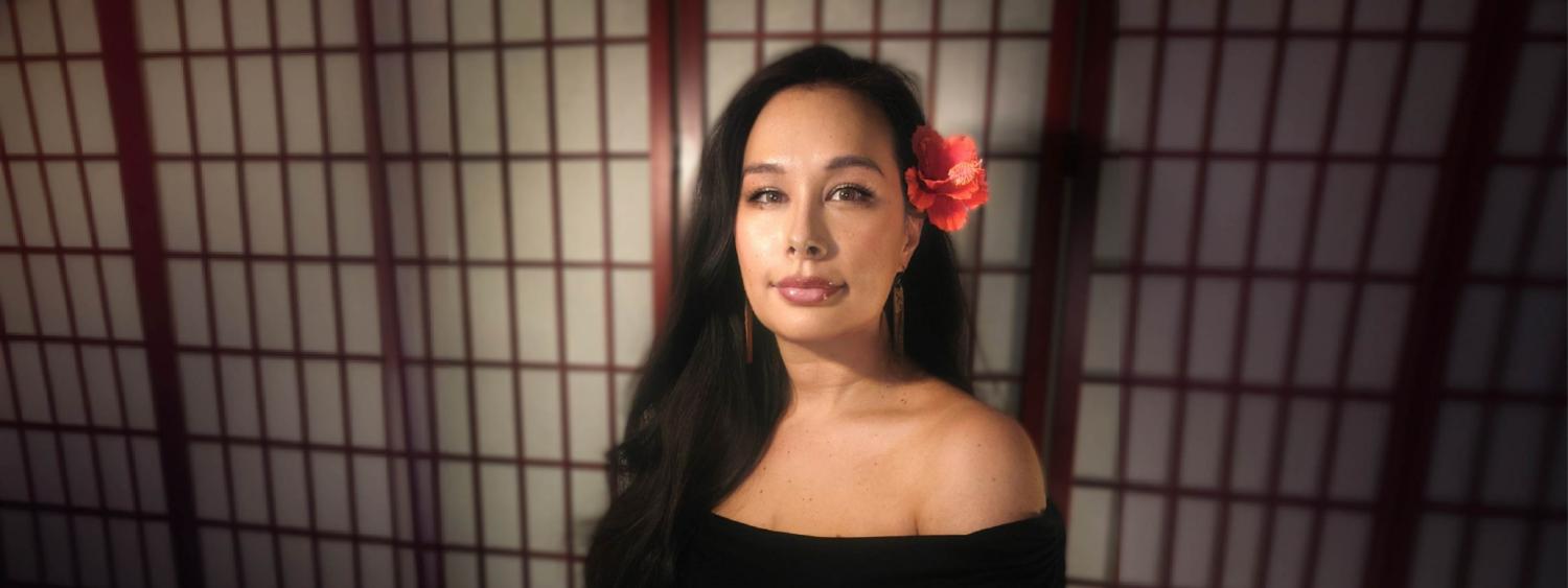 Woman wearing black with flower tucked behind her left ear
