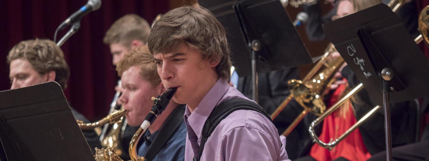 Focus on male saxophone player in performance with other students