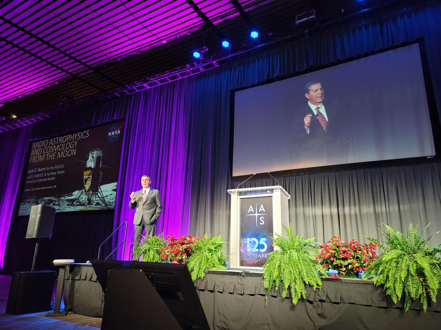 Photo of Jack Burns on stage giving a talk at the AAS meeting