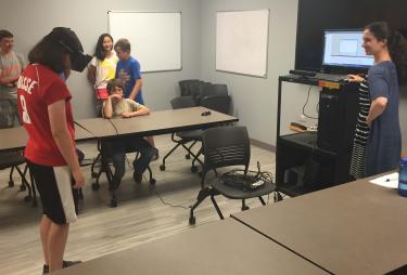 Megan demonstrates the use of the VR to a group of students