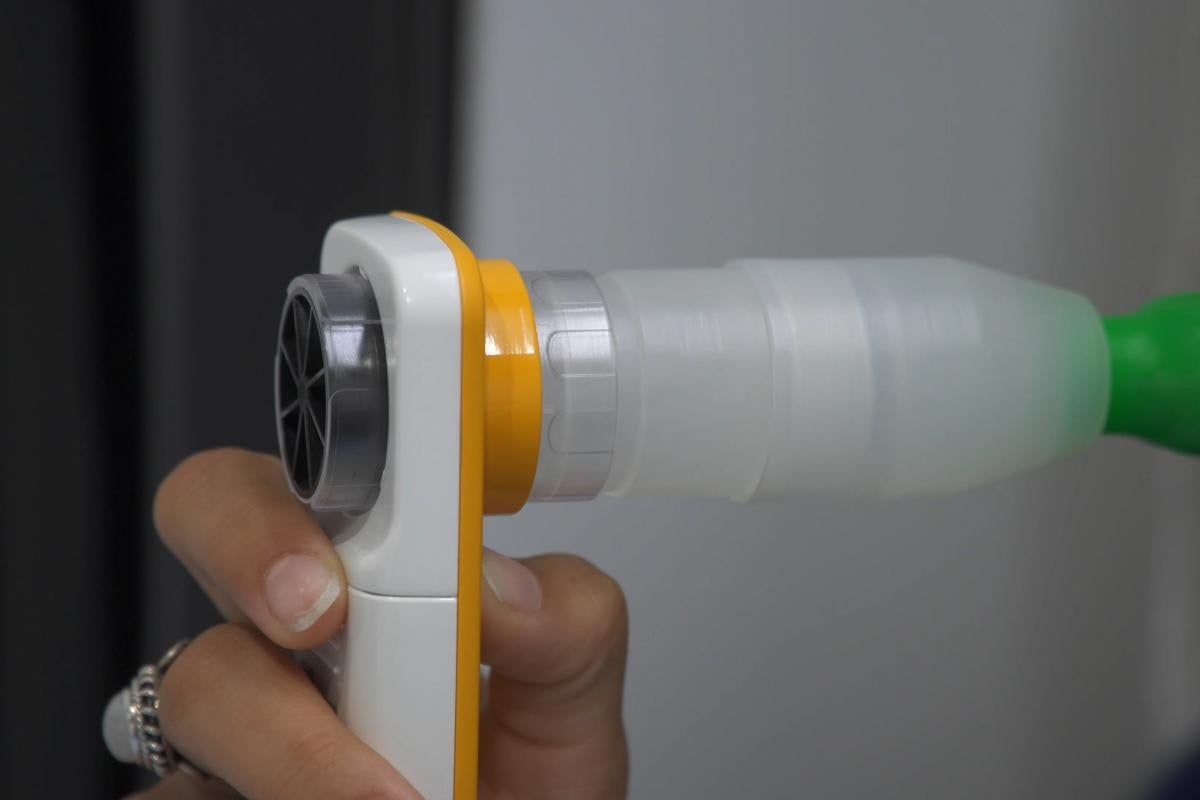 A breathalyzer device held in someone's hand. The image is cropped so you cannot see who is using the device.