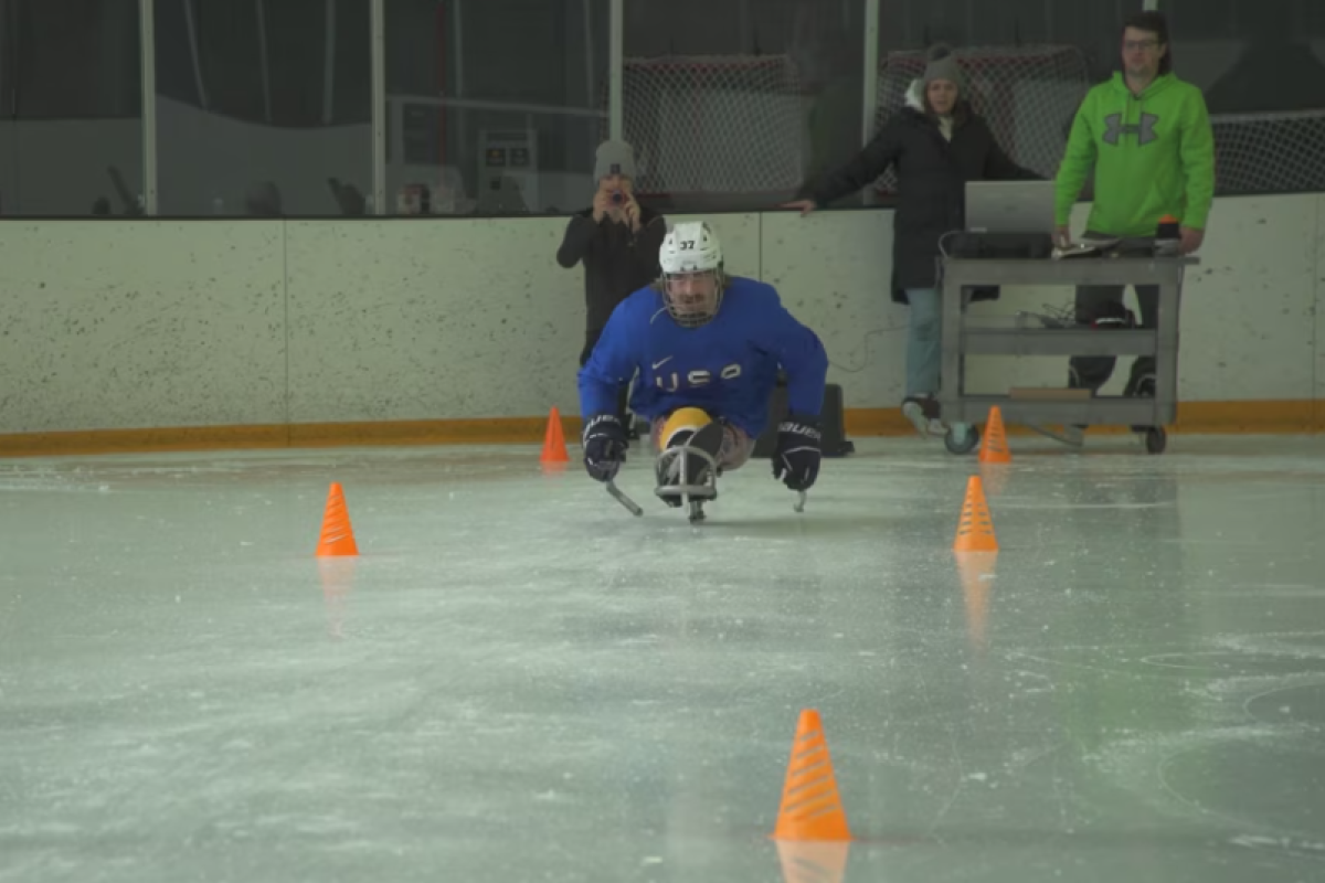 A sled hockey athlete participating on an ice rink course.