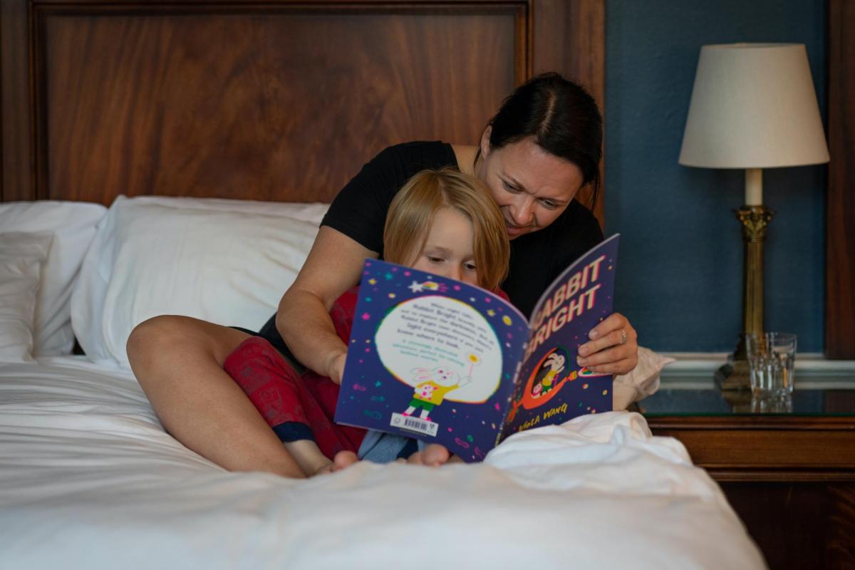 Caregiver and child sitting in bed reading bedtime story