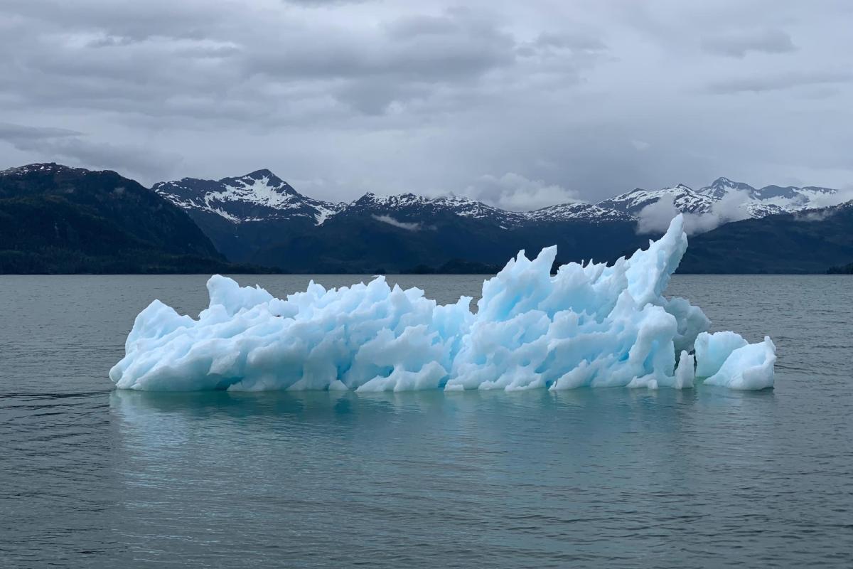 A melting glacier in a lake with mountains in the background