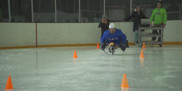 A sled hockey athlete participating on an ice rink course. 