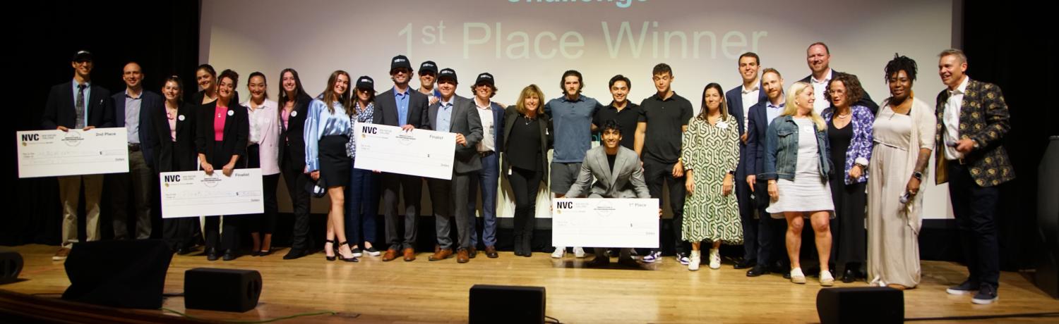Group poses on stage with prize checks