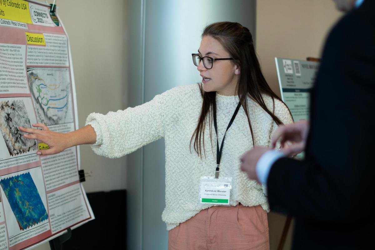 A girl points to a poster that displays her research project