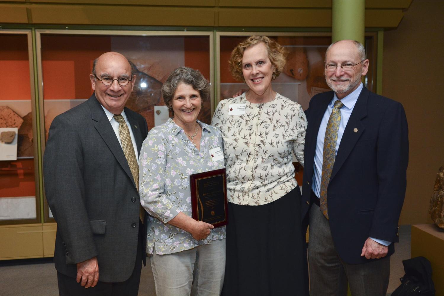 A group poses together with a plaque commemorating an award