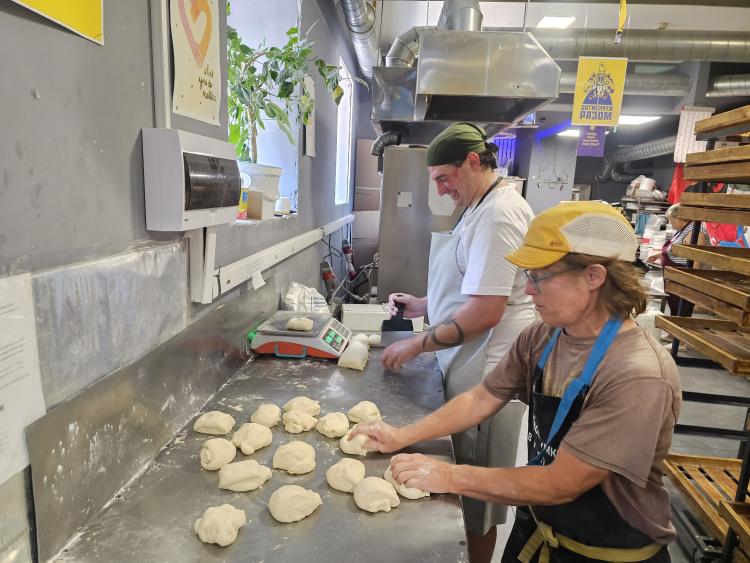 A man and a woman portion and shape balls of dough