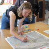 A college aged girl leans over a table, drawing sharpie dots on a map of Keystone, CO