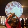 a young girl holds up a stuffed jaguar to a large projector moon at the Fiske Planetarium