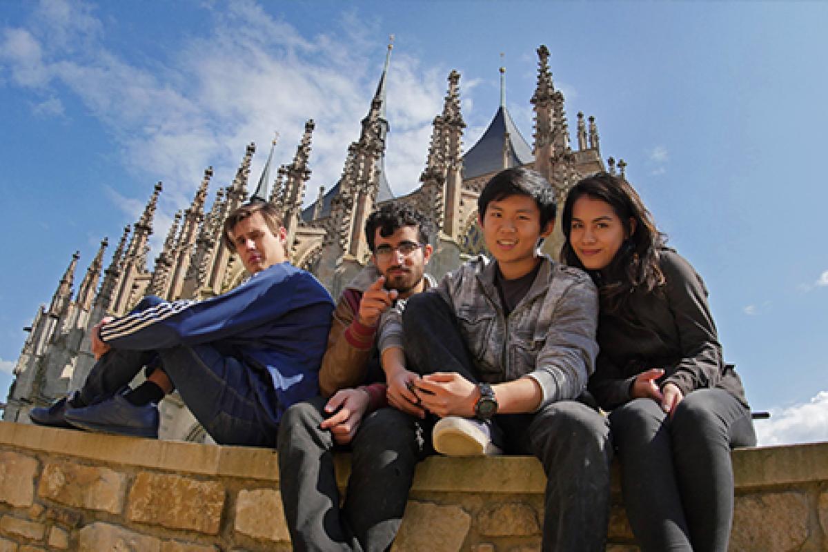 Students sitting on a wall in front of a cathedral