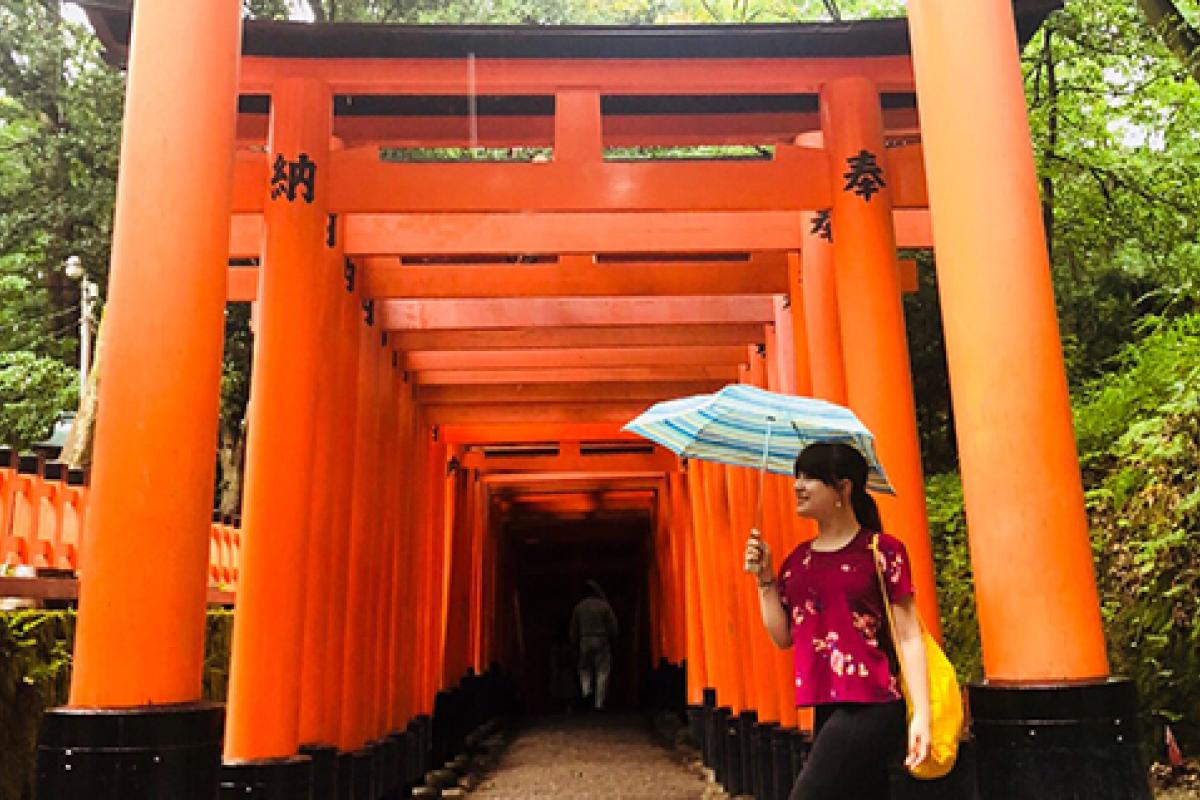 Studetn walking by Tori Shrines in Japan with umbrella