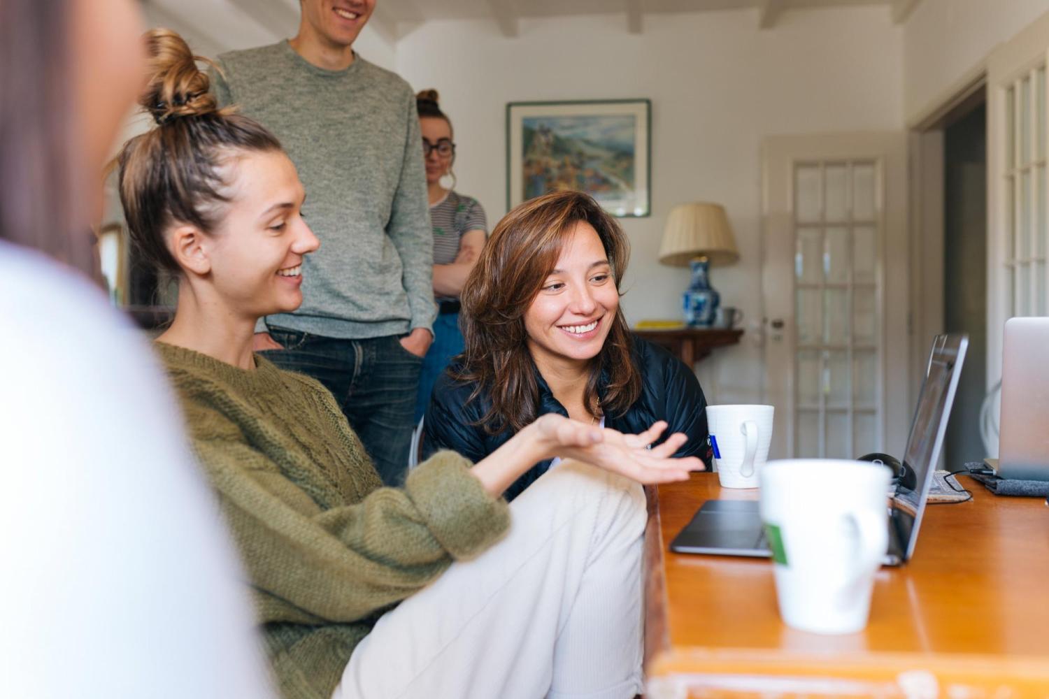 A girl and her family gather around a laptop.