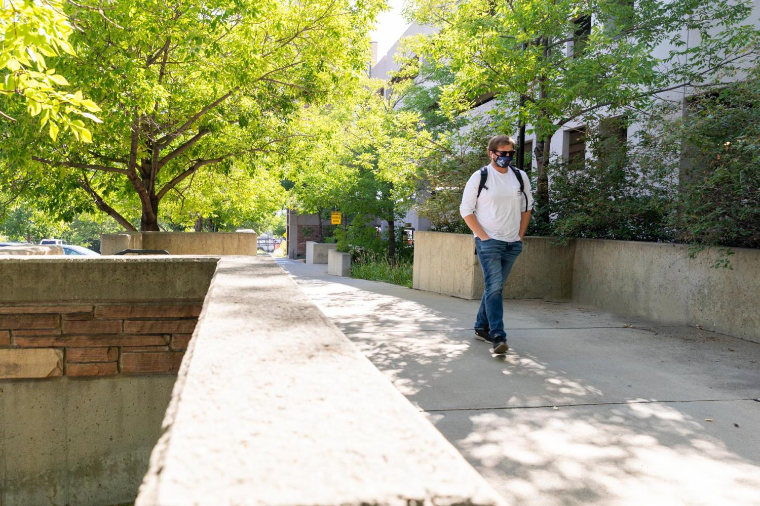 Student walking down the sidewalk with a mask