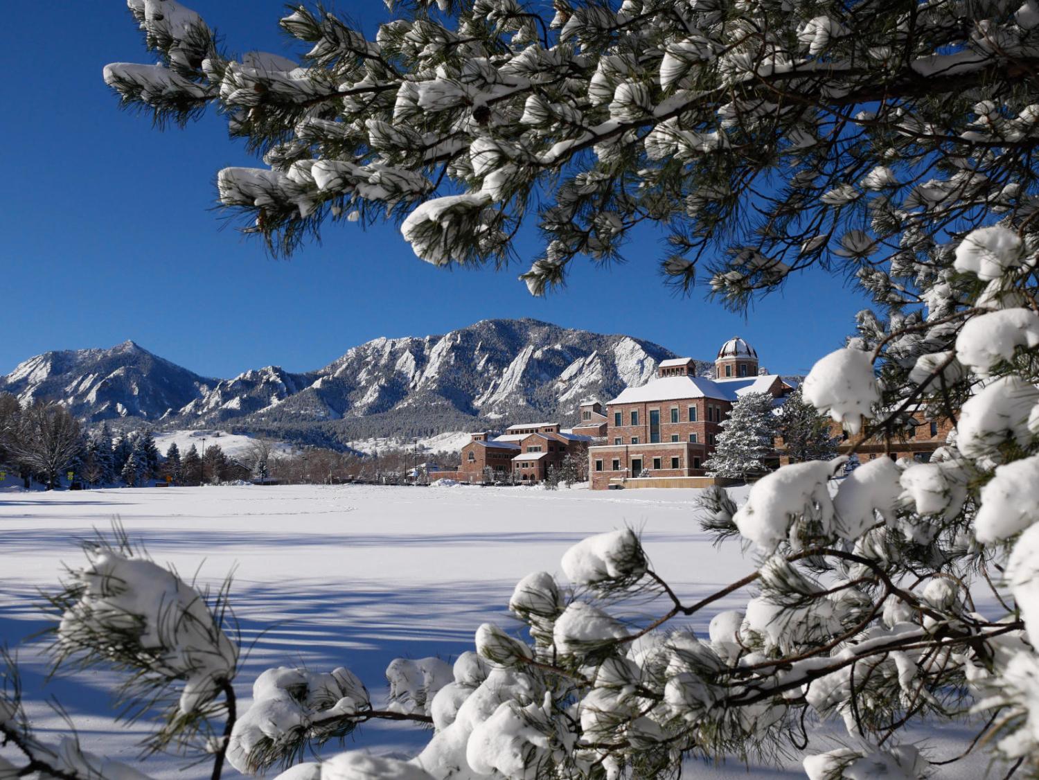 View of the CU Boulder engineering field, Koelbel building, C4C and Flatirons after snowfall.