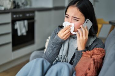 Person blowing their nose while talking on the phone