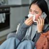 Person blowing their nose while talking on the phone