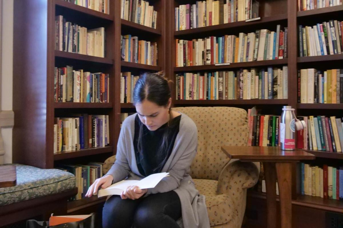 A student reading surrounded by books.