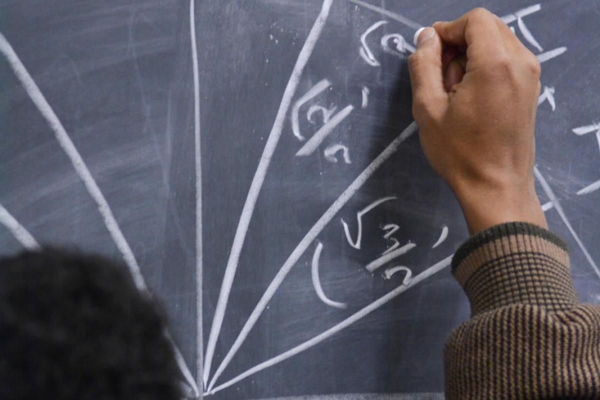 A student doing a math problem on a chalk board