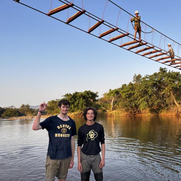 Marlin and Josh posing under travel team doing work pushing cross beams out