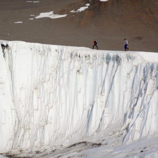2 people walking across glacier