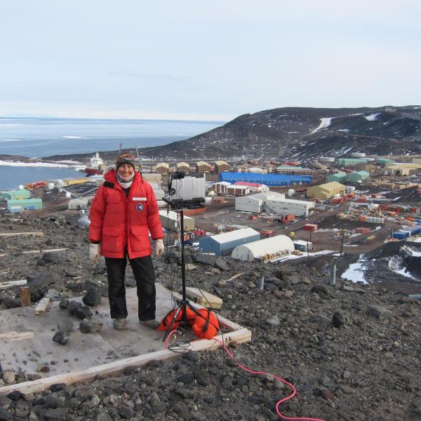 Scientist standing on Observation Hill with a computer on a stand and McMurdo station in the background