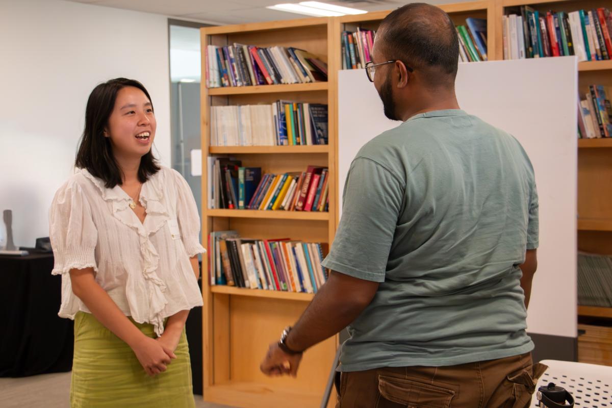 A young woman greets and smiles at a man across from her