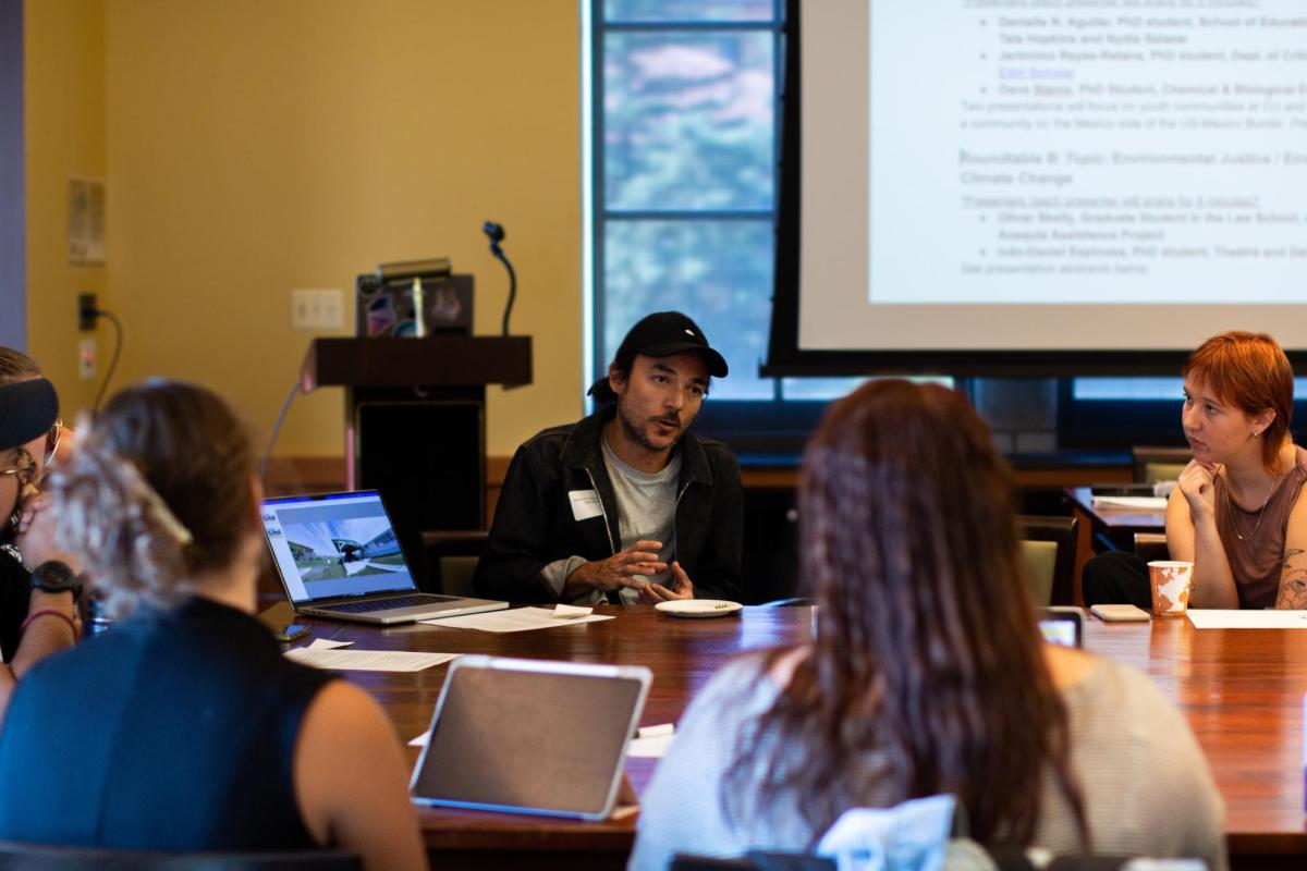 a student presents his research to a group of students at a table