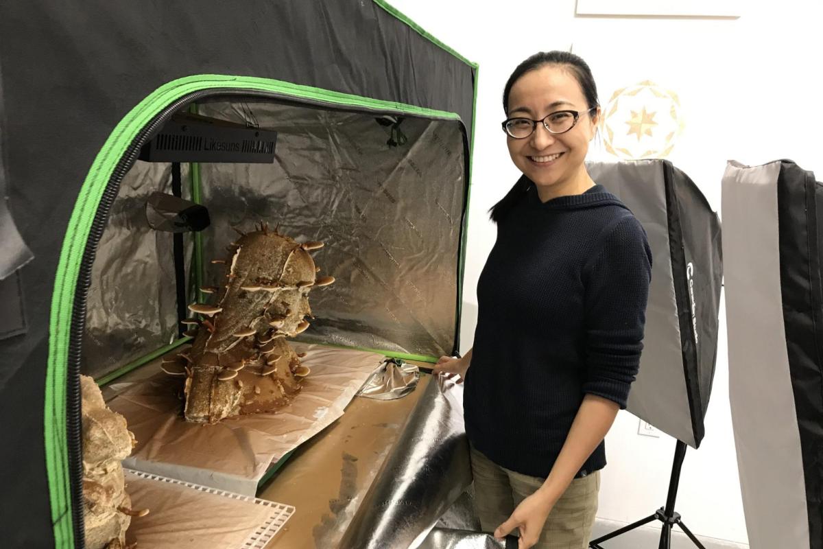 Xiojing Yan stands next to her mushroom sculpture