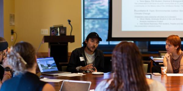 a student presents his research to a group of students at a table