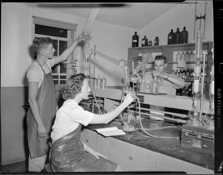 Black and white photograph of a group of students handling lab equipment in a chemistry lab