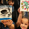 Kids hold up paintings they made